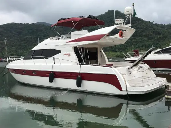 Lancha de 48 pés branca com detalhes em vinho atracada em marina de Angra dos Reis