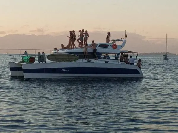 Catamarã Power Cat 40 ao entardecer com pessoas relaxando no convés, perfeito para passeios de barco no Rio de Janeiro.