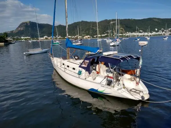 Veleiro Farr 38 fundeado em enseada com outros veleiros ao redor, bimini azul e morros ao fundo