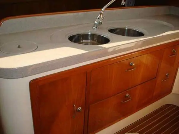 Detalhe da pia dupla de inox na cozinha do Catamarã Dolphin 46, com armários de madeira
