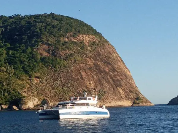 Catamarã Power Cat 40 em águas cristalinas cercadas por montanhas, ideal para aluguel de barco e passeios privativos.