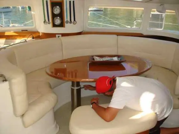 Salão interno do Catamarã Dolphin 46 com sofá e mesa de madeira durante inspeção