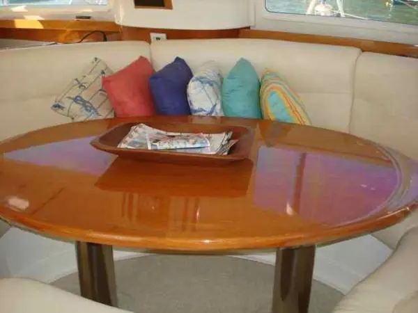 Detalhe da mesa central de madeira e almofadas coloridas no salão do Catamarã Dolphin 46