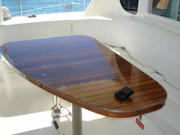 Mesa de madeira polida na área externa do Catamarã Dolphin 46, ideal para refeições durante o passeio