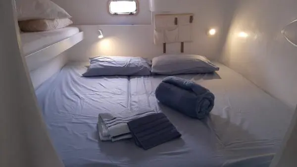 Suíte confortável no Catamarã Power Cat 40 com cama de casal e iluminação aconchegante, perfeita para pernoite em passeios de barco.