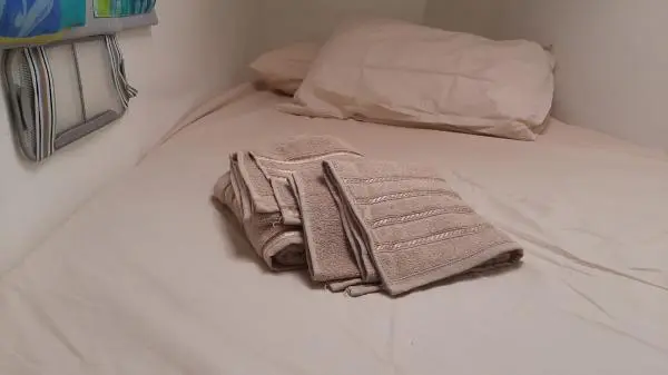Toalhas dobradas sobre uma cama no Catamarã Power Cat 40, destacando o conforto e a atenção aos detalhes nos passeios de barco.