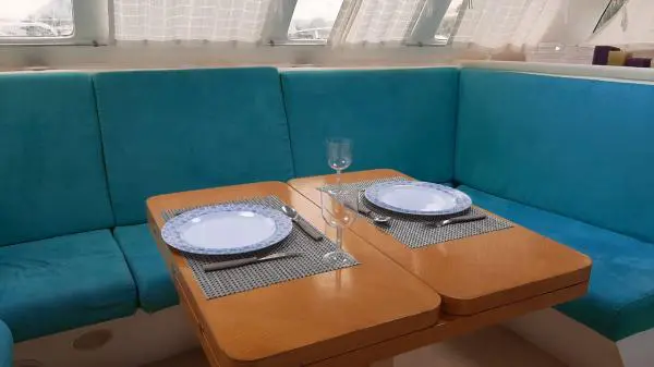 Mesa preparada com pratos e taças no Catamarã Power Cat 40, destacando o conforto para passeios e eventos exclusivos.