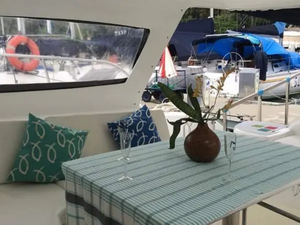 Mesa decorada com flores e taças na área interna do Catamarã Power Cat 40, destacando conforto e elegância.