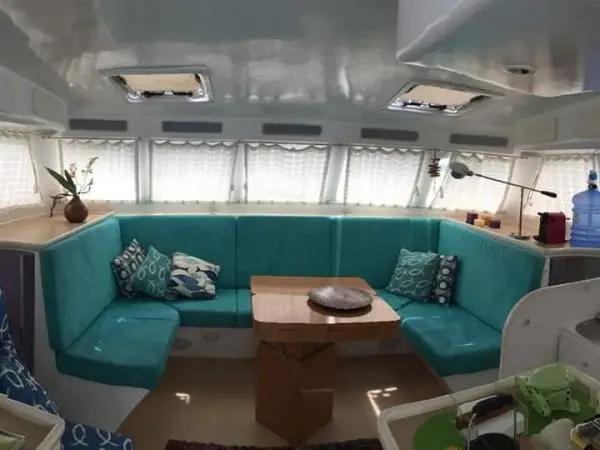 Sala de estar com decoração aconchegante no interior do Catamarã Power Cat 40, ideal para aluguel de barco com conforto.