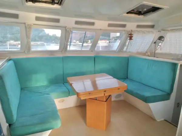 Área interna aconchegante do Catamarã Power Cat 40 com assentos estofados, ideal para relaxar em passeios de barco.