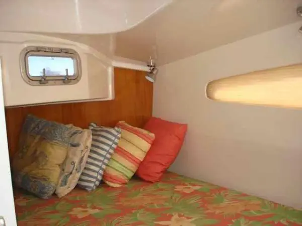 Cabine de casal do Catamarã Dolphin 46 com travesseiros coloridos e janela lateral