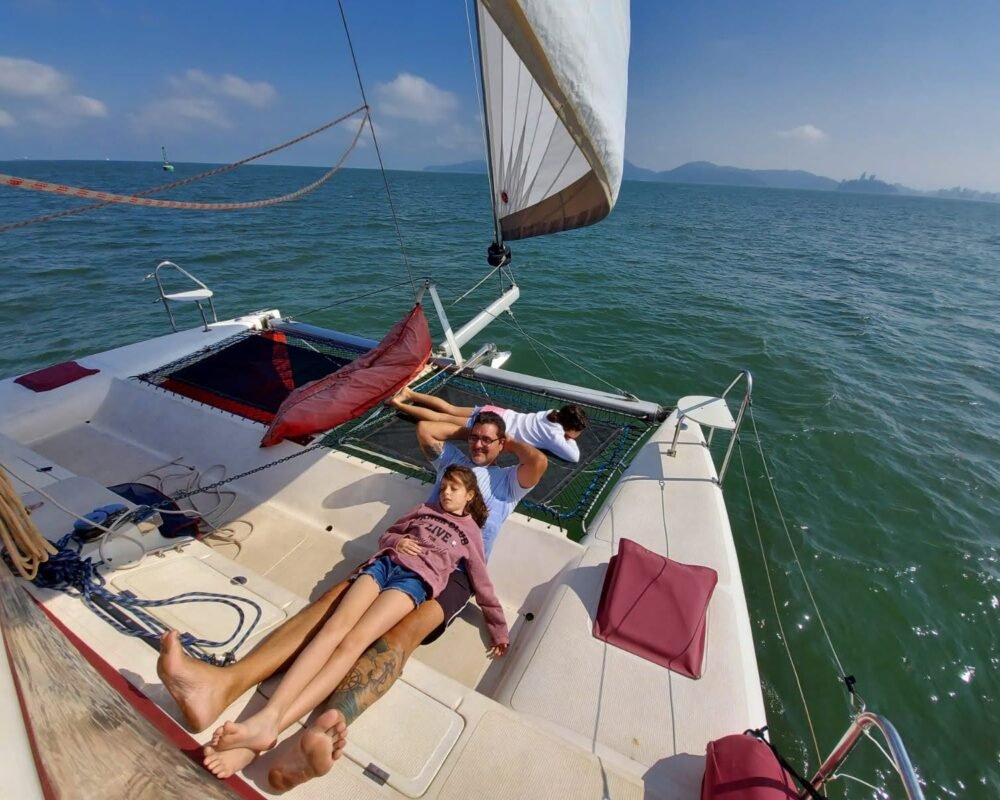 família relaxando no deck frontal do catamarã com vela içada