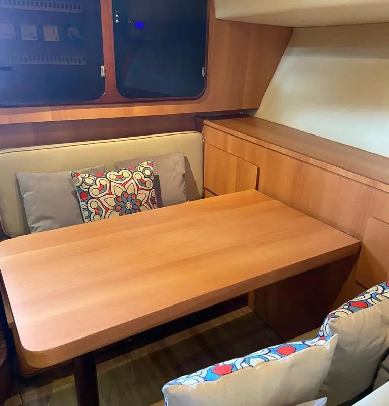 Área interna da Lancha Rio Star 50 com mesa para refeições e decoração aconchegante.