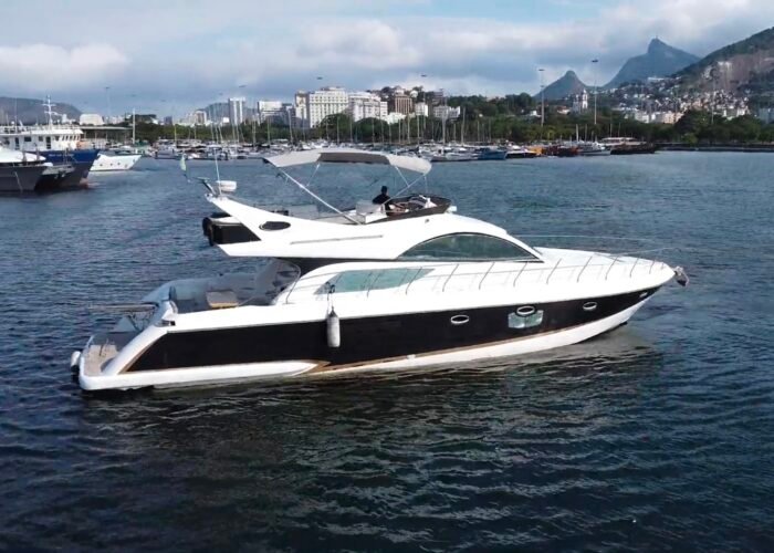 Iate Polo 600 de casco preto e branco navegando na Baía de Guanabara, com Corcovado e marina ao fundo