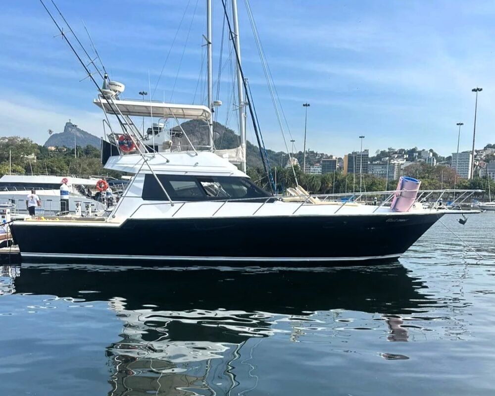 Lancha Rio Star 50 de casco preto atracada em marina no Rio de Janeiro, com o Corcovado ao fundo