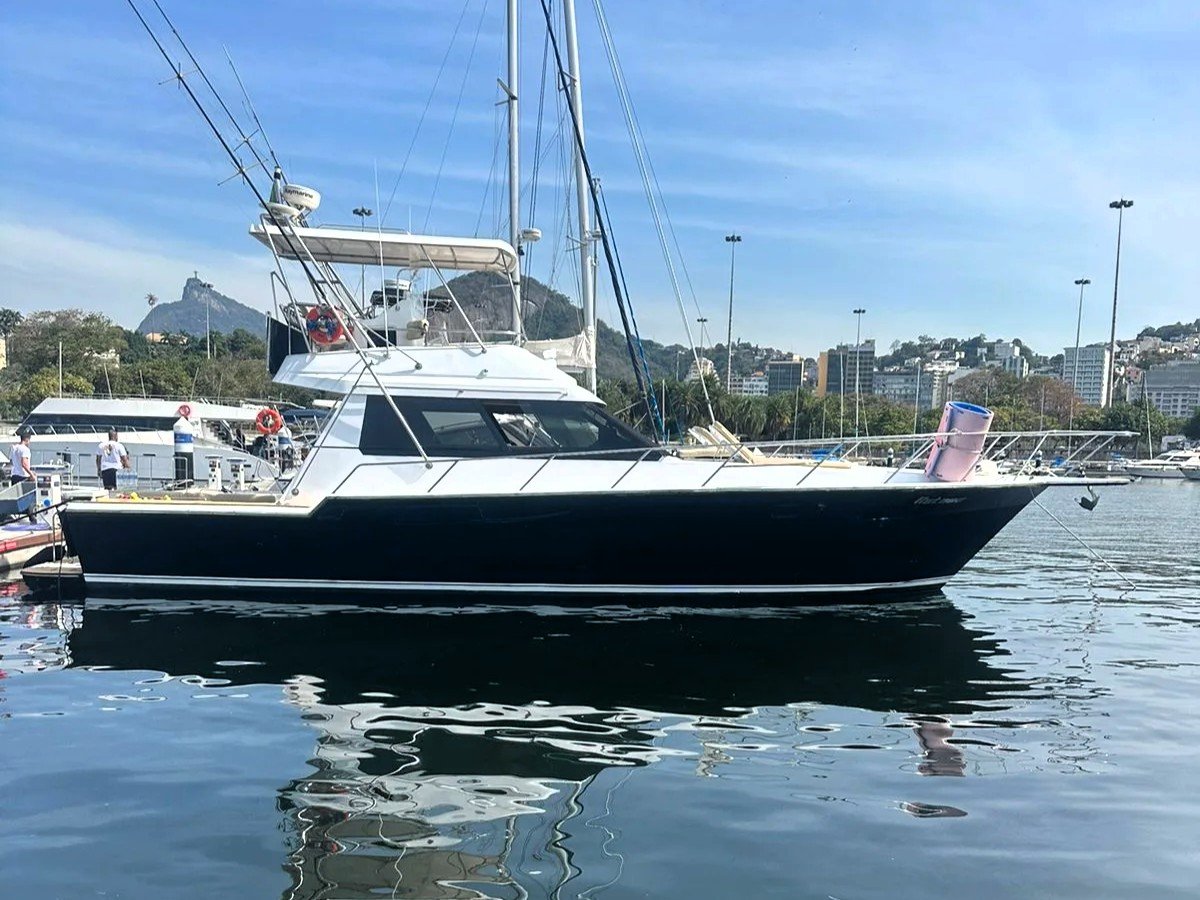 Lancha Rio Star 50 de casco preto atracada em marina no Rio de Janeiro, com o Corcovado ao fundo