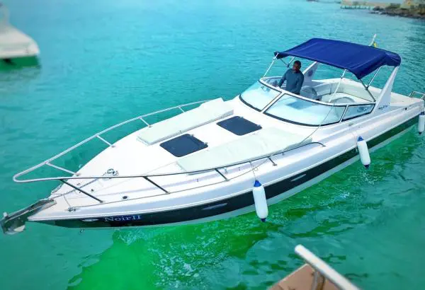 Lancha Coral 30 atracada em marina com toldo azul e águas esverdeadas