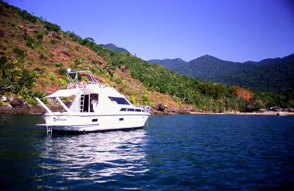 Lancha Intermarine Oceanic 36 navegando em Ilhabela próxima à praia e mata atlântica.