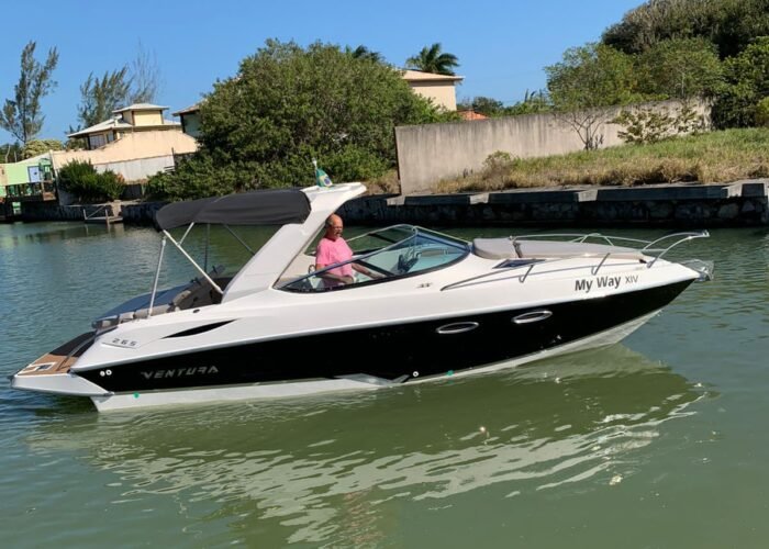 lancha Ventura 265 de perfil em canal, com casco preto e branco, toldo preto e plataforma de popa