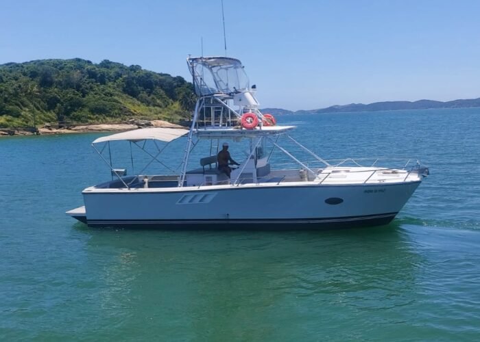 Lancha catamarã ancorada em águas verde-turquesa próximas a costa verde de Búzios