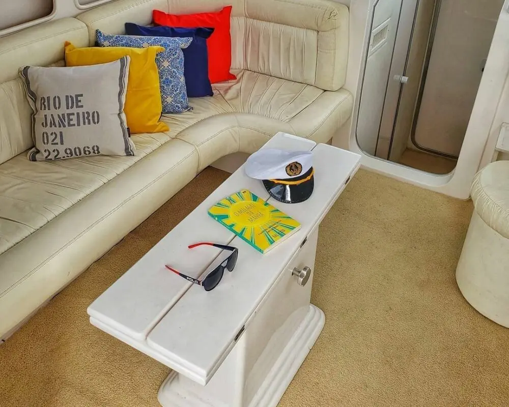 Sala interna da lancha Oceanic 36 com sofá e mesa, ideal para momentos de conforto durante aluguel de lancha no Rio de Janeiro.
