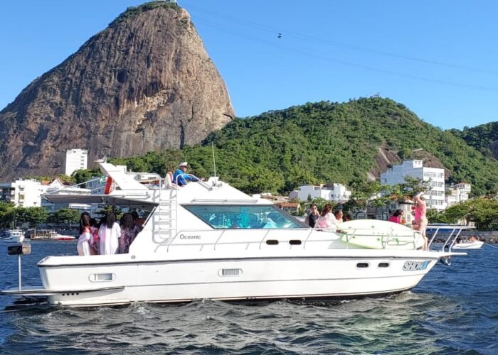 Lancha Oceanic 36 navegando com grupo a bordo e o Pão de Açúcar com o bondinho ao fundo