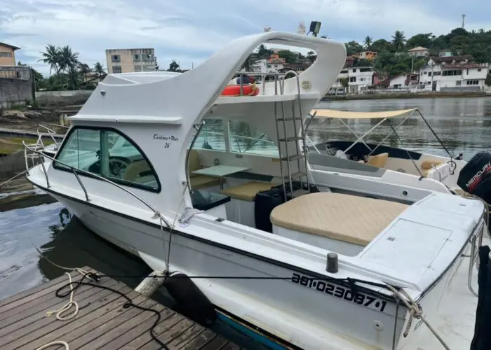 Lancha Carbrasmar branca atracada em píer de madeira, com hardtop, cabine envidraçada e solário de popa