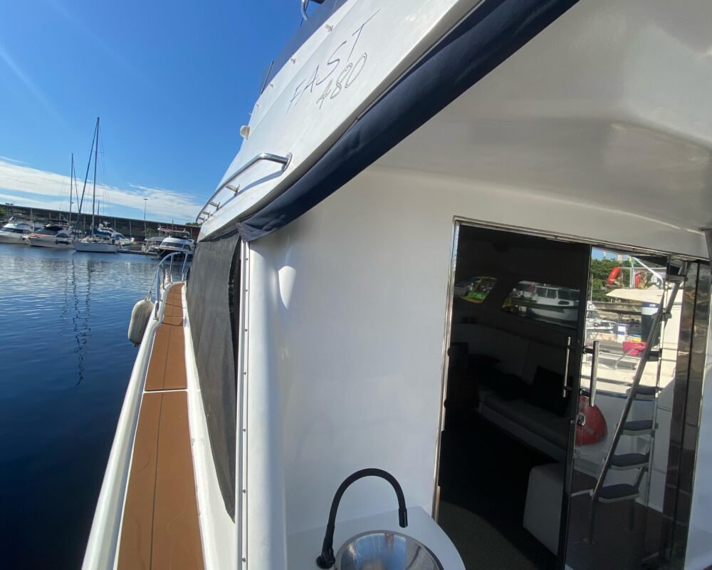 Lateral da lancha com pia externa e passarela que dá acesso à proa, garantindo comodidade aos passageiros. O barco oferece um passeio confortável e elegante.