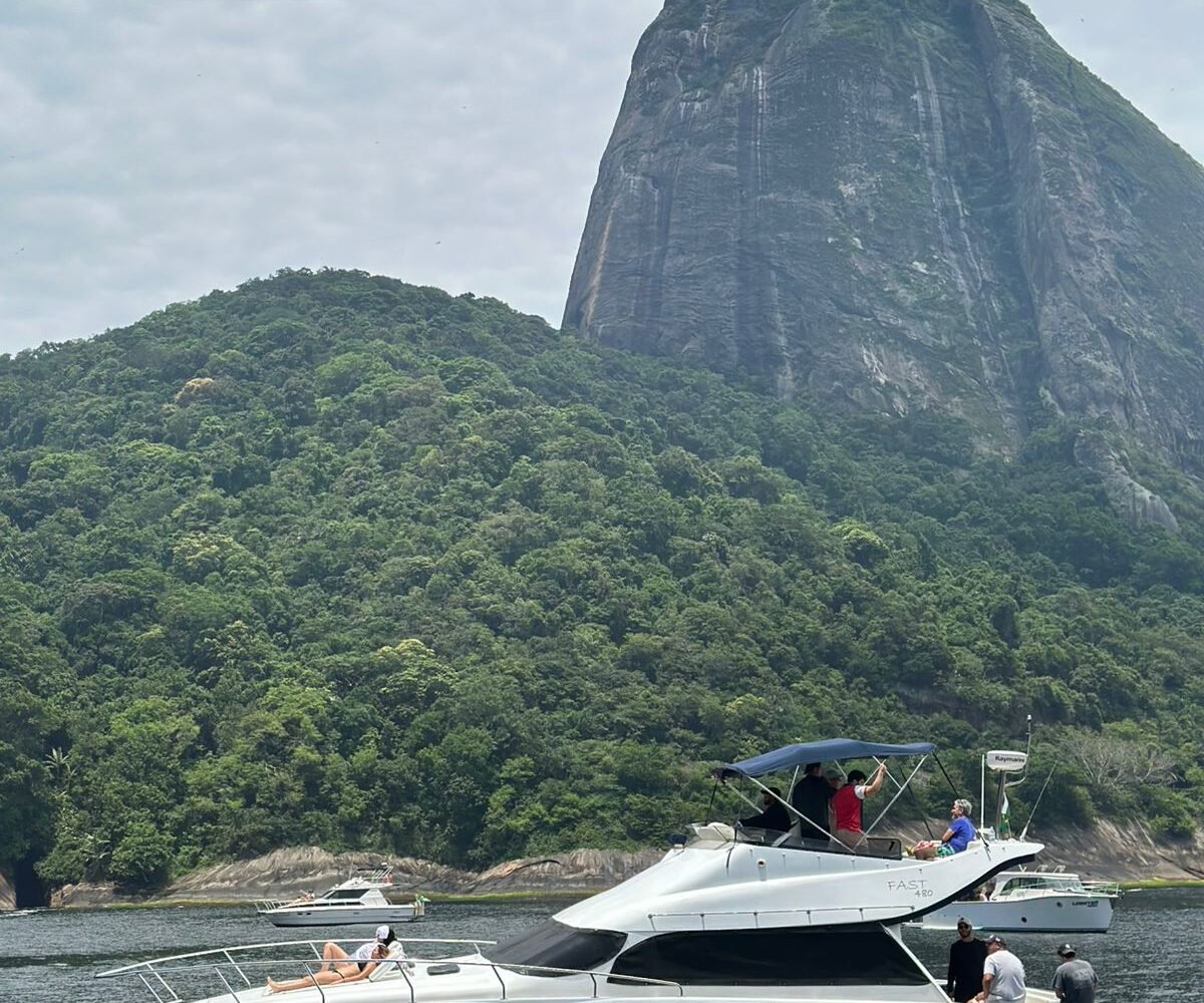 Lancha Fast Senna 48 fundeada em enseada, com casco azul-escuro e flybridge coberto por bimini