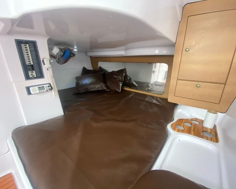 Quarto de uma lancha com uma cama marrom ao centro.
