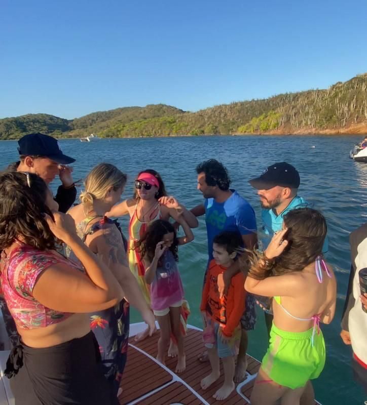 Grupo de pessoas conversando em pé na popa de uma lancha.