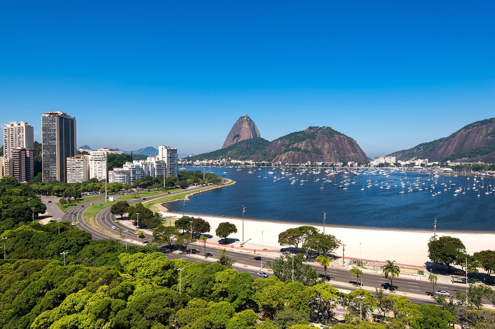 Vista panorâmica da Enseada de Botafogo, no Rio de Janeiro, com o Pão de Açúcar ao fundo e diversos barcos ancorados na baía.