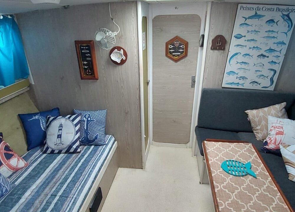 Sala completa da lancha com sofá, cama e parede decorada