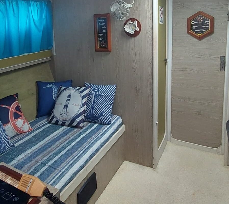 Sala completa da lancha com sofá, cama e parede decorada