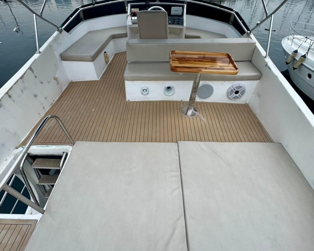 Flybridge com amplo solário acolchoado, assentos confortáveis e uma vista privilegiada da marina.