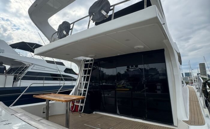 Popa da lancha Tecnomarine 50 com assento estofado, mesa de apoio e acesso ao flybridge por escada lateral.