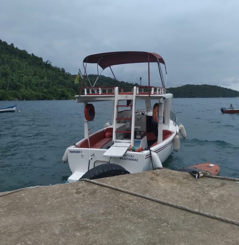 Barco traineira ancorado próximo ao cais em Paraty, pronto para embarque.