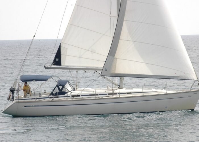 Veleiro Bavaria de 44 pés navegando a vela aberta em mar calmo, com tripulante ao leme.