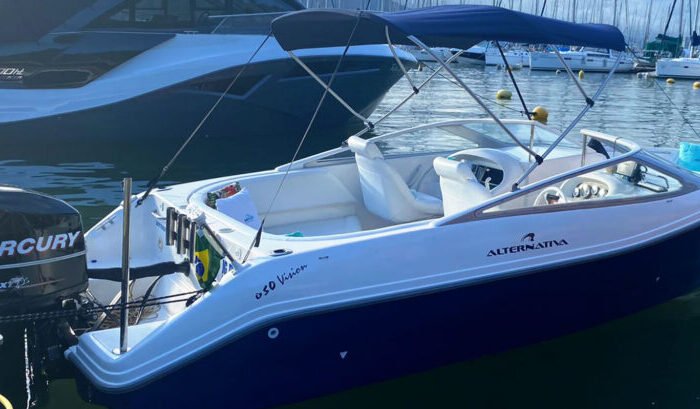 Lancha Alternativa 21 atracada na marina, vista lateral com casco azul, toldo e motor de popa