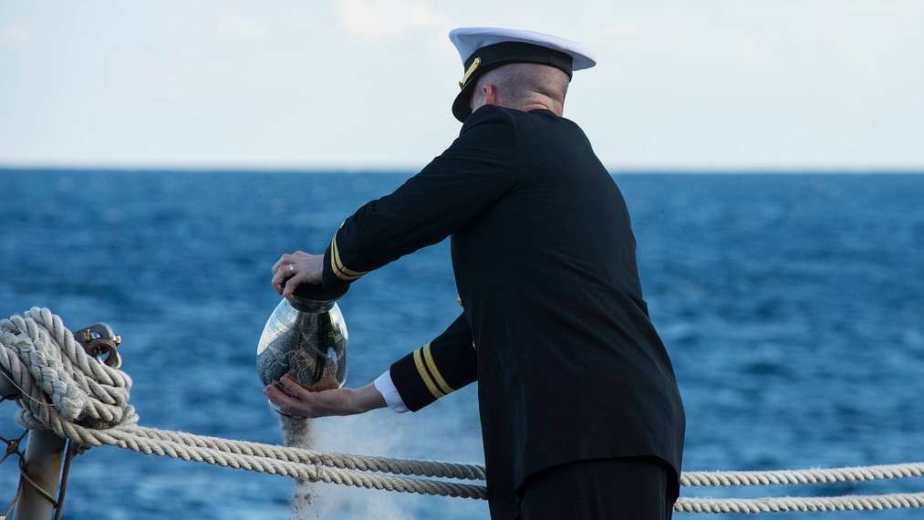 Oficial naval realiza cerimônia de dispersão de cinzas no mar.