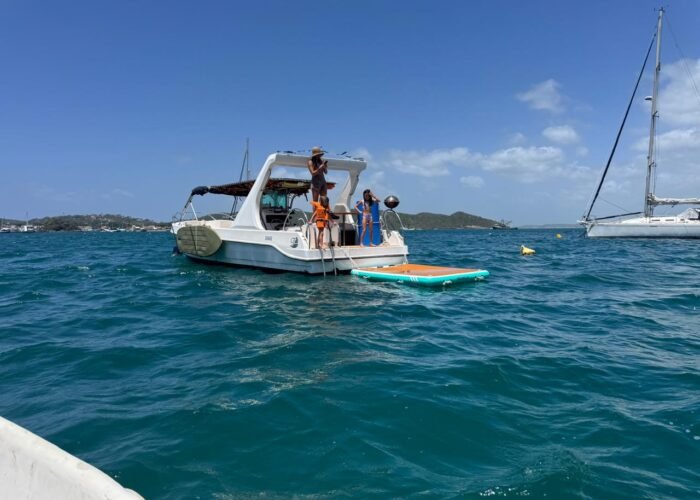 Lancha CF 34 Golden Fish V ancorada em Búzios com plataforma inflável montada e passageiros na popa