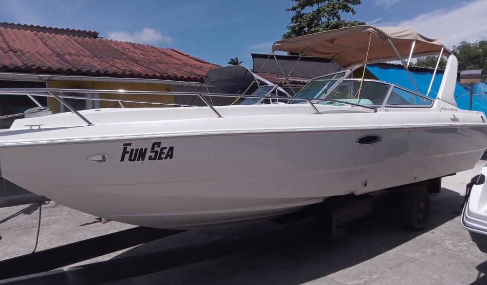 Lancha Tecnoboat 26 branca em pátio náutico, vista lateral com toldo bimini bege e para-brisas