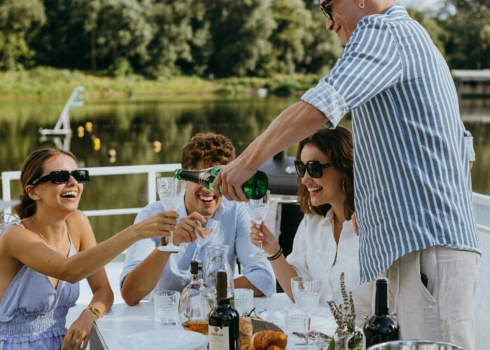 Looks para festa no barco de dia: grupo de amigos com roupas leves em tons claros, óculos de sol e taças