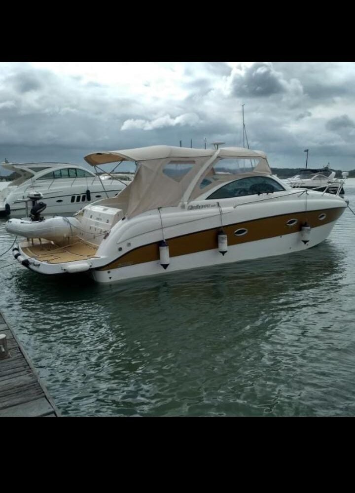 Lancha V ancorada em Salvador, com design elegante e teto rígido para proteção solar.