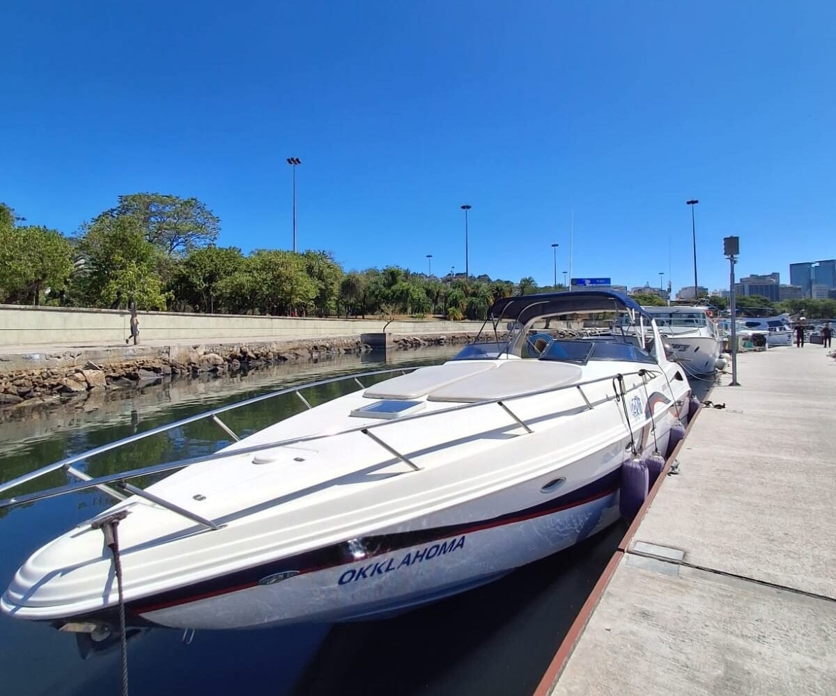 Lancha Runner 380 branca atracada no píer da marina, vista da proa, sob céu limpo