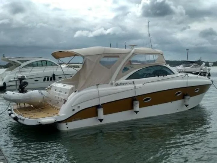 Lancha Cimitarra 34 Caribé atracada em marina, com capota e plataforma de popa