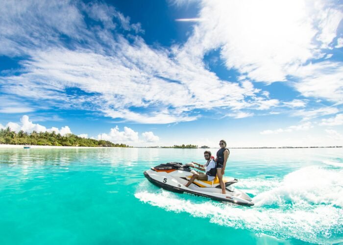 Jet ski em movimento em mar aberto com a costa ao fundo em dia de sol