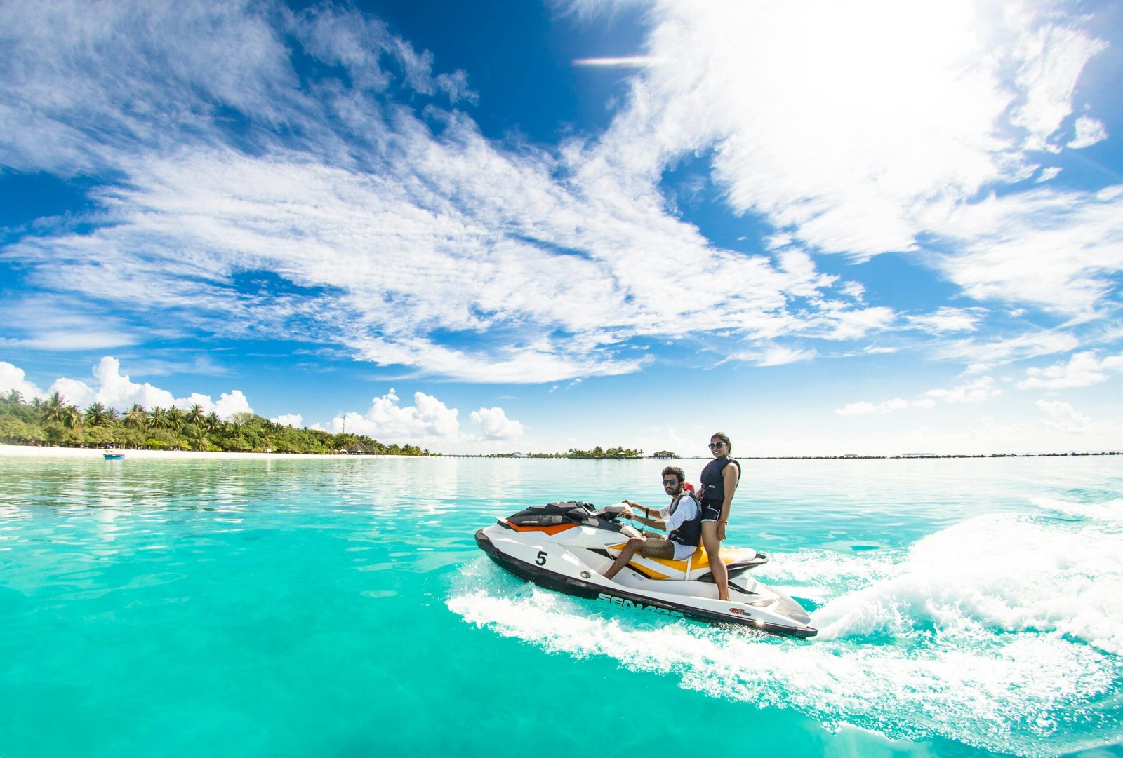 Jet ski em movimento em mar aberto com a costa ao fundo em dia de sol