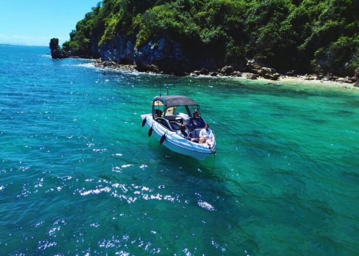 Lancha Coral 24 ancorada em uma enseada de águas cristalinas em Búzios, proporcionando um passeio relaxante com vista para a costa.