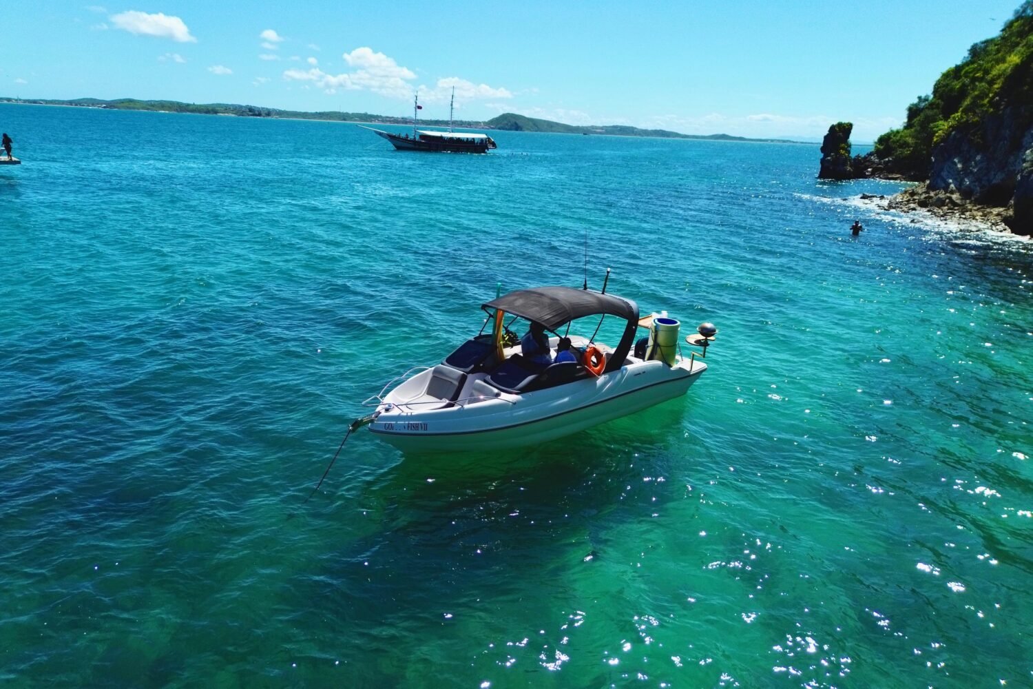 Lancha Coral 24 ancorada próxima a uma praia paradisíaca, com mar azul-turquesa e vegetação exuberante ao fundo.